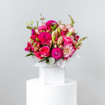 flowers pink and magenta with foliage arranged in a white short flower box